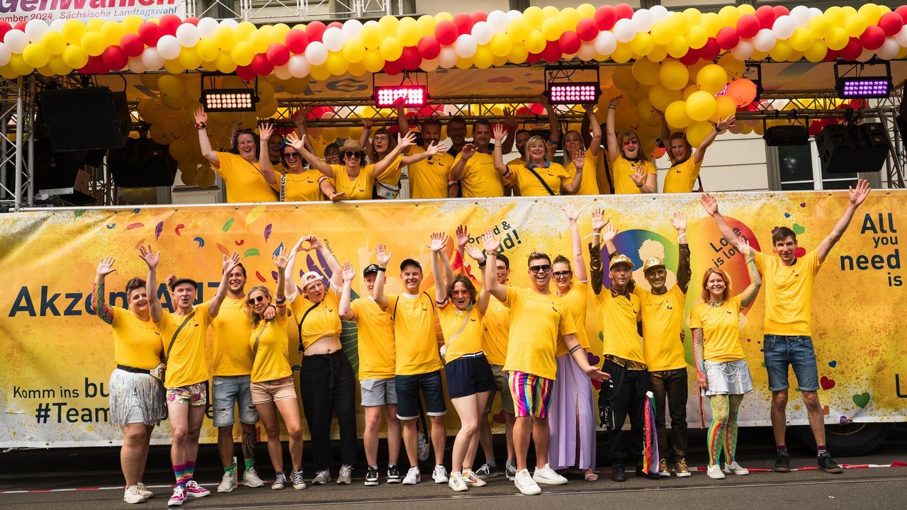 Die Teilnehmer:innen vor dem CSD-Truck. Alle in gelben Shirts.